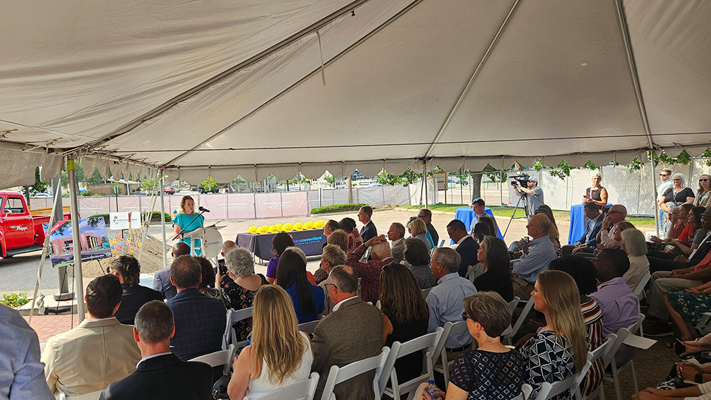 a crowd listening to a speaker at the groundbreaking ceremony