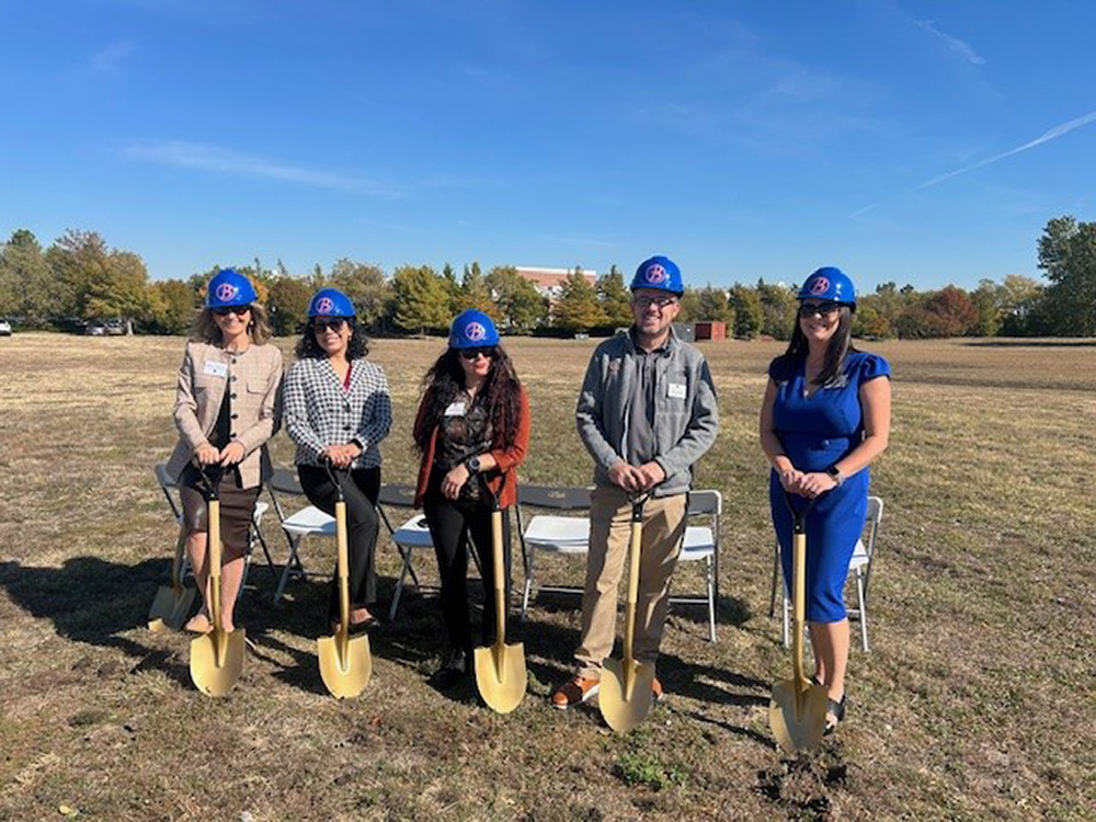 a group of people pose with shovels at the groundbreaking ceremony