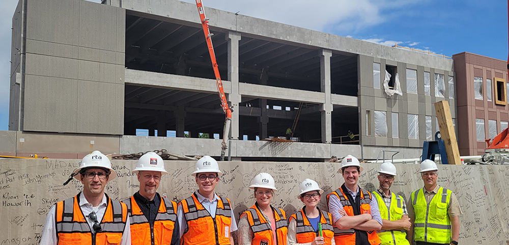 group from rta and hcda standing in front of the signed beam at the palmer high school construction site